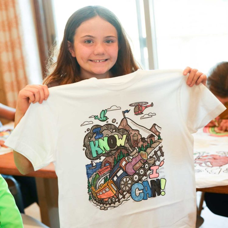 "Photo of kid showing and smiling her Doodle Tees 'I Know I Can' colored shirt"